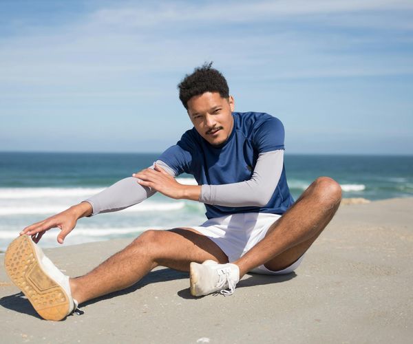 Person stretching energetically outdoors in the morning sun.